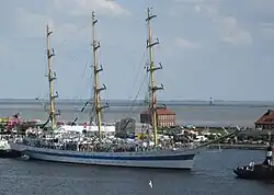 Blick vom Riesenrad über den Großen Hafen mit dem russischen Segelschulschiff MIR und den Südstrand in Richtung Südost; im Hintergrund der Jadebusen
