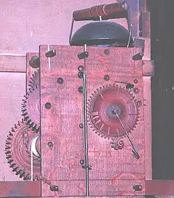 Hölzernes Bodenstanduhrwerk, Schlossscheibe mit relativ tiefen Lücken, z. Zt. der Aufnahme wird 11 Uhr geschlagen