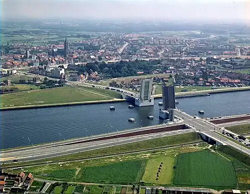 Zelzate mit dem Kanal Gent–Terneuzen und der Zelzatebrug im Vordergrund im Jahr 1970, die Freiflächen im Hintergrund sind der verfüllte Kanalverlauf von 1894