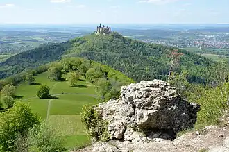 Albtrauf und Vorbergzone der Zollernalb: Blick vom Zeller Horn (913 m), auf den Zollerberg (858 m), mit Burg Hohenzollern. Im Vordergrund die Zellerhornwiese