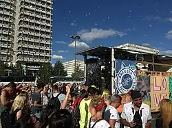 Eine Demonstration durch eine größere Straße, ein „Party“-Anhänger mit Lautsprechern und Bannern fährt mit, auf dem Anhänger sind unter anderem die Buchstaben L O V E