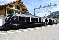 Gleicher Zug wie im Bild vorher, vom Ende aus gesehen. Die MOB-Lok, die den Zug durch die Umspuranlage und weiter nach Montreux schieben wird, fehlt noch, ist links auf separatem Gleis abgestellt.