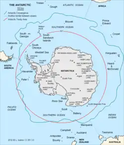 Ein Bild des Kontinent Antarktika und der umliegenden Inseln. Eingezeichnet sind verschiedene Ortsnamen, ein roter Kreis um Antarktika auf Höhe der 60-Grad-Marke und in blau, teilweise weiter außen als der rote Kreis, teilweise weiter innen die antarktische Konvergenz.